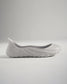 A minimalist gray slip-on shoe with a unique contoured design and textured sole exemplifying modern footwear aesthetics