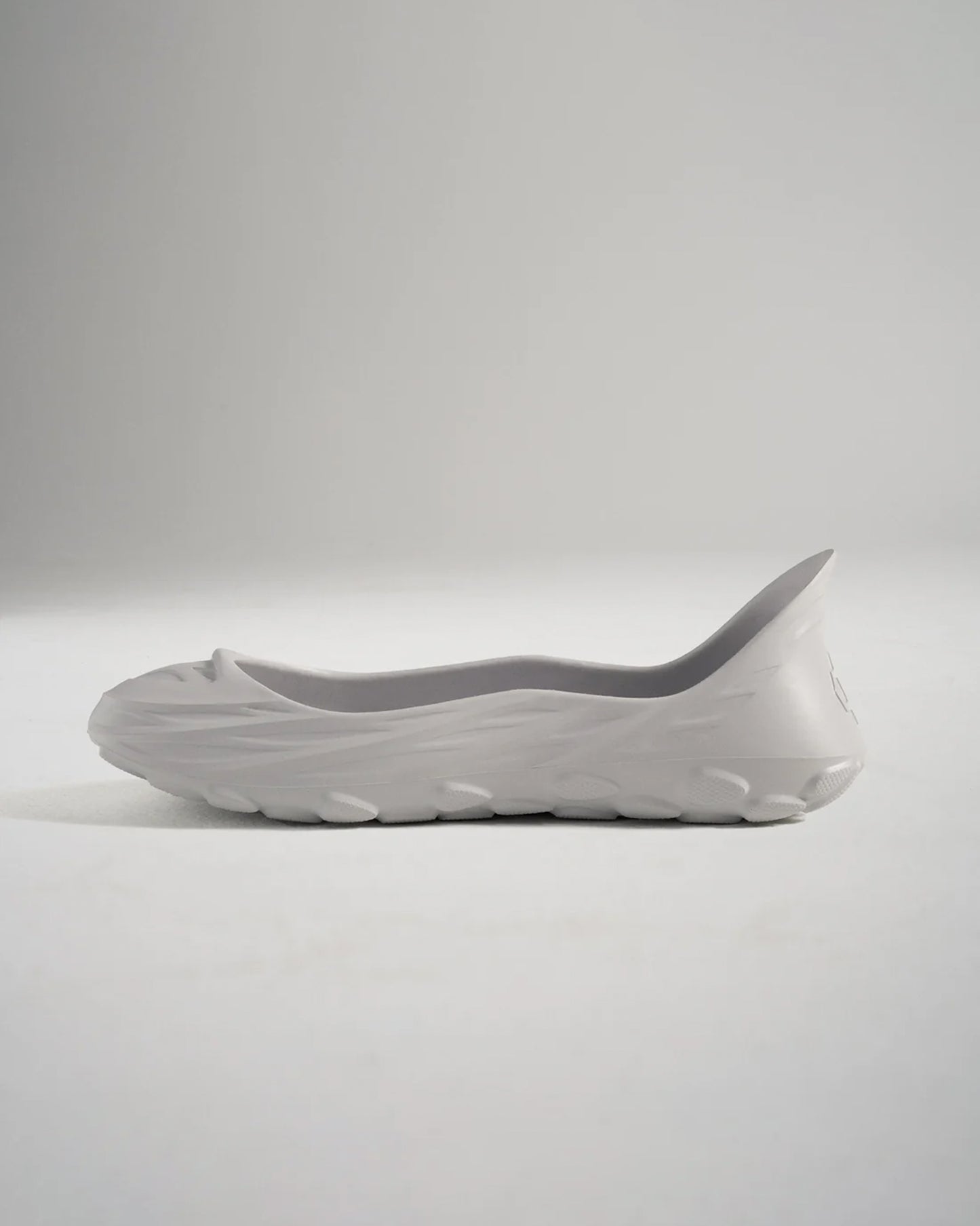 A side view of a minimalist gray slip-on shoe with a sleek design and textured sole perfect for casual wear