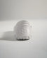 A minimalist white athletic shoe viewed from the back featuring a textured sole and a geometric logo on the heel