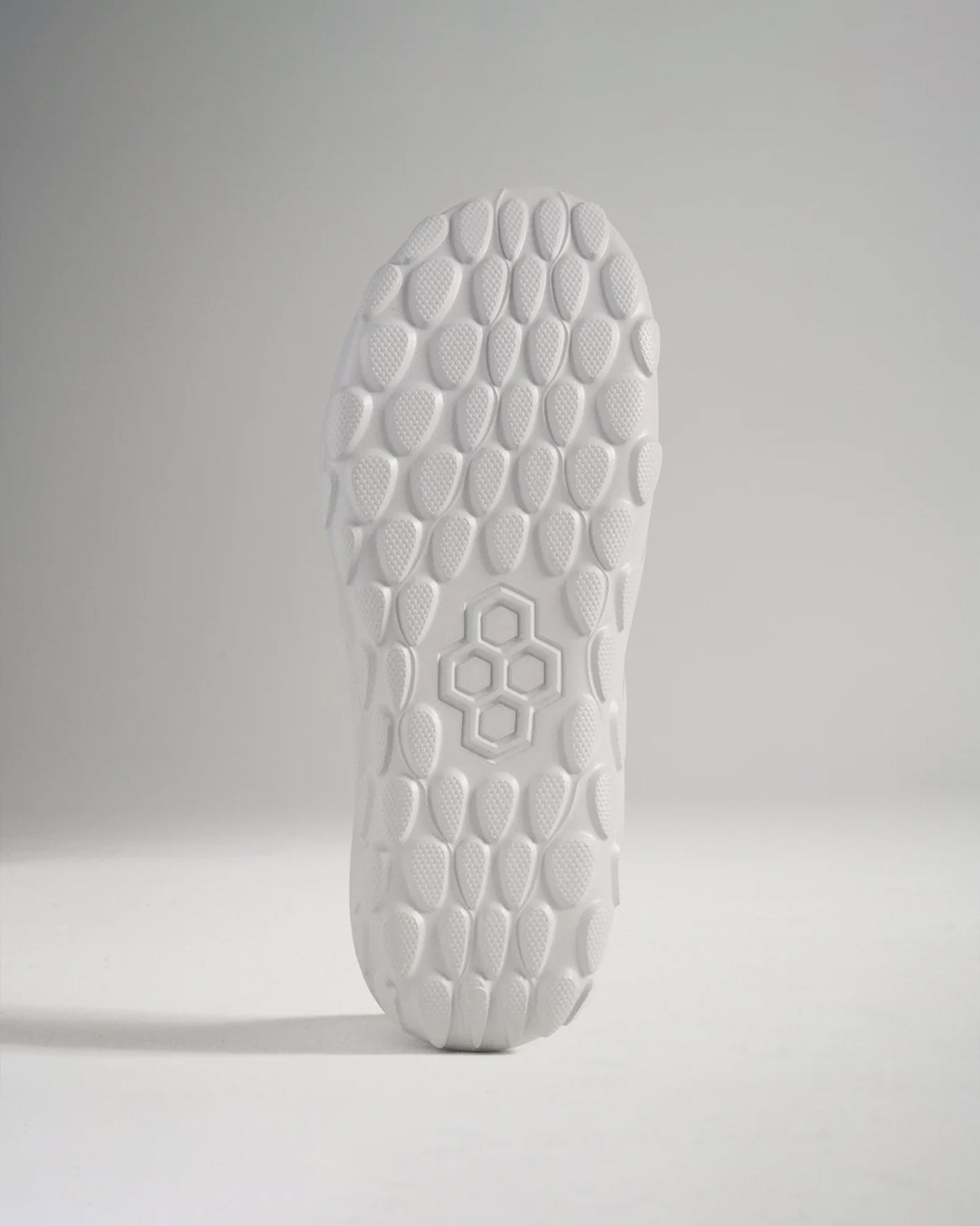 A close-up view of a white athletic shoes sole featuring a textured hexagonal pattern designed for superior grip and traction