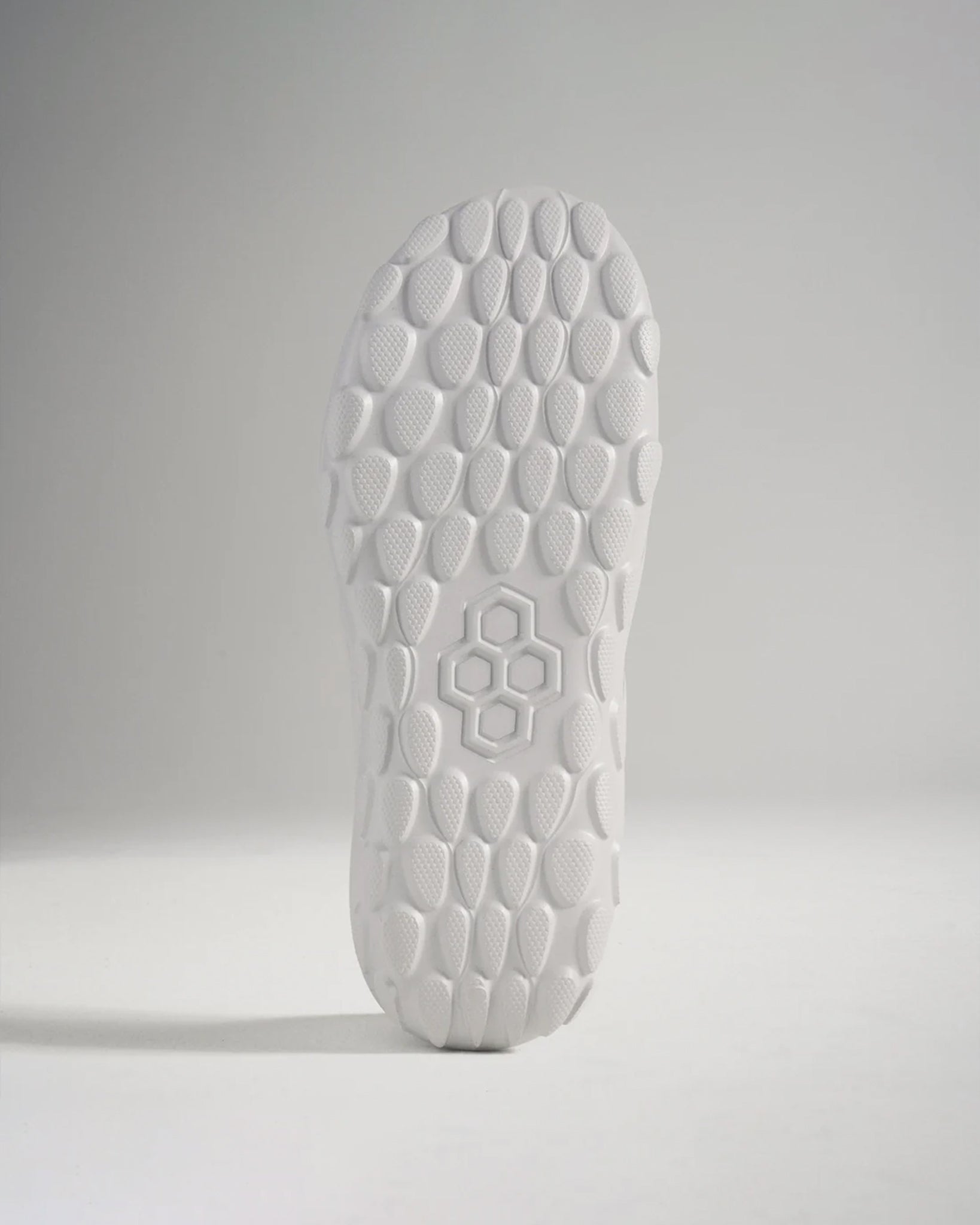 A close-up view of a white athletic shoes sole featuring a textured hexagonal pattern designed for superior grip and traction