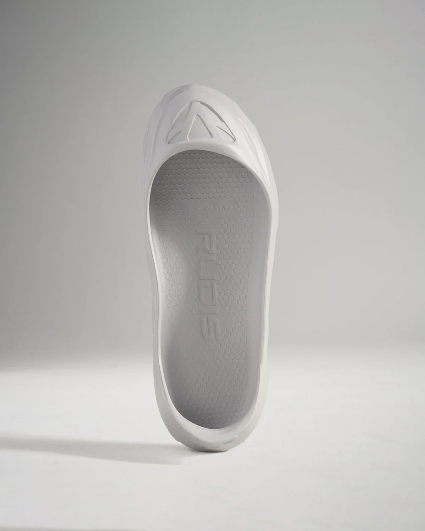 A minimalist white shoe with a sleek design and textured sole ideal for lightweight performance