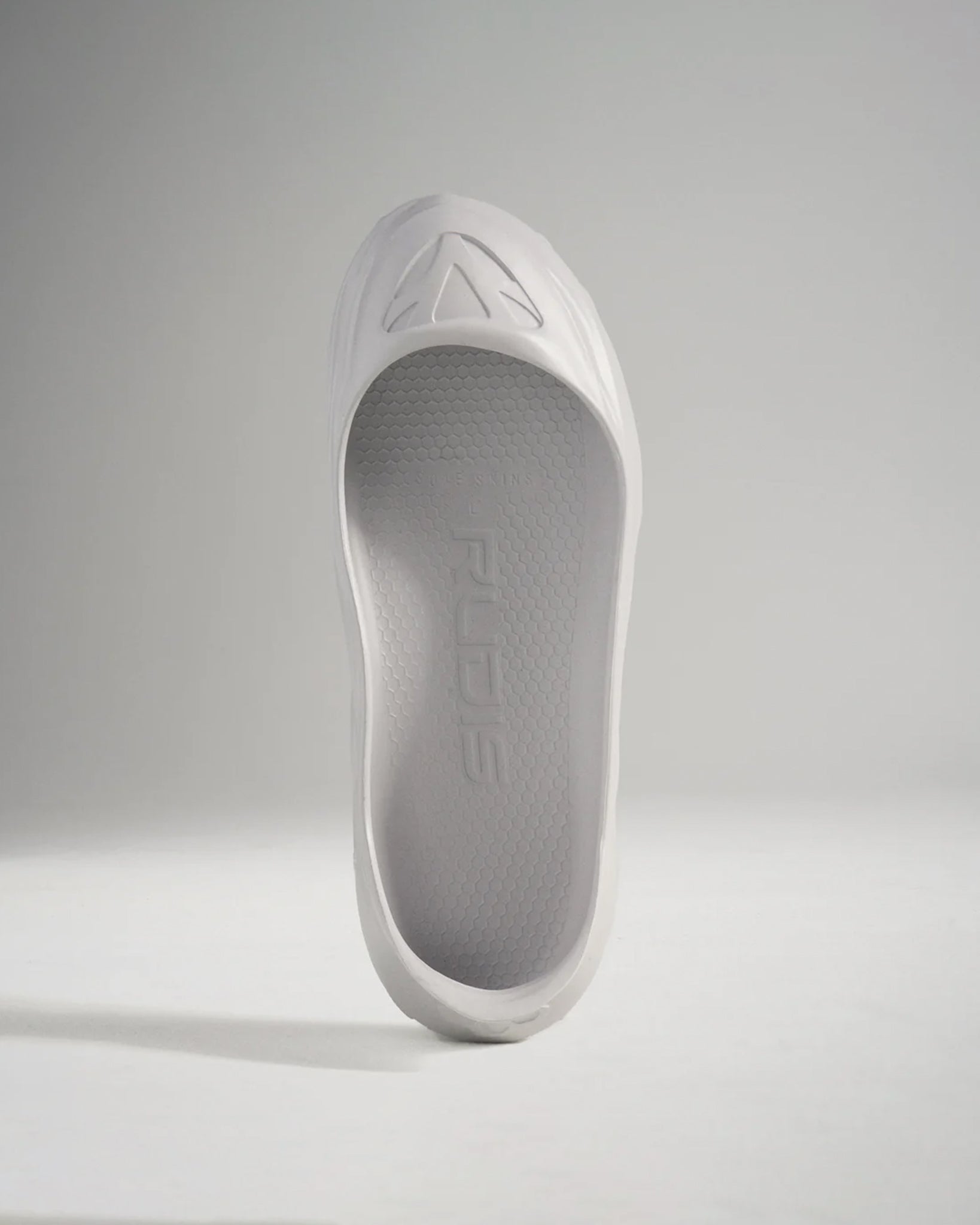 A minimalist white shoe with a sleek design and textured sole ideal for lightweight performance