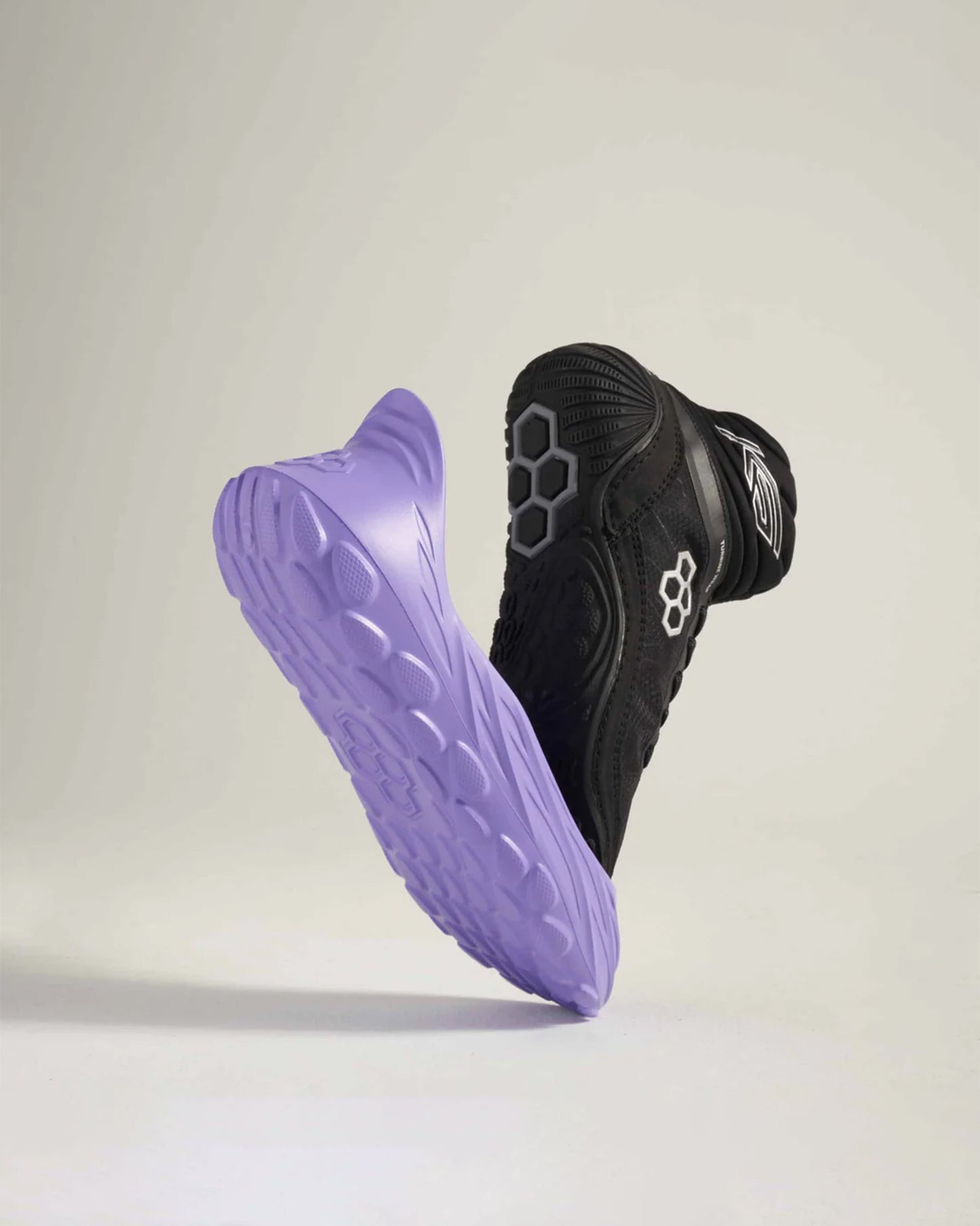 This image displays a pair of athletic shoes known for their innovative design featuring a sleek black upper and a distinctive purple sole with a textured surface for improved grip