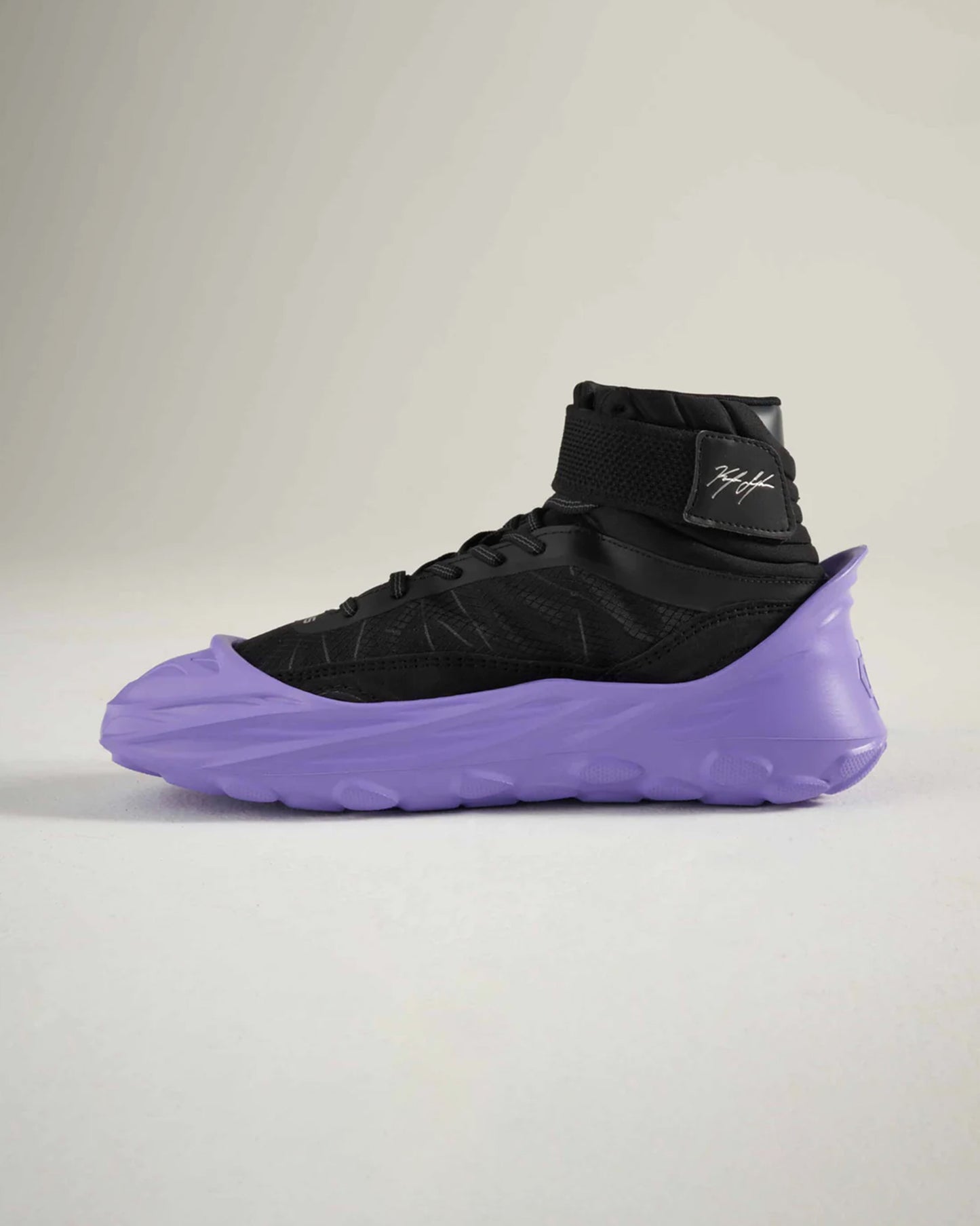 A modern high-top sneaker featuring a black upper and a distinctive purple sole emphasizing a stylish and athletic design