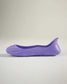 A side view of a sleek purple rubber shoe featuring a minimalist design and textured sole for grip