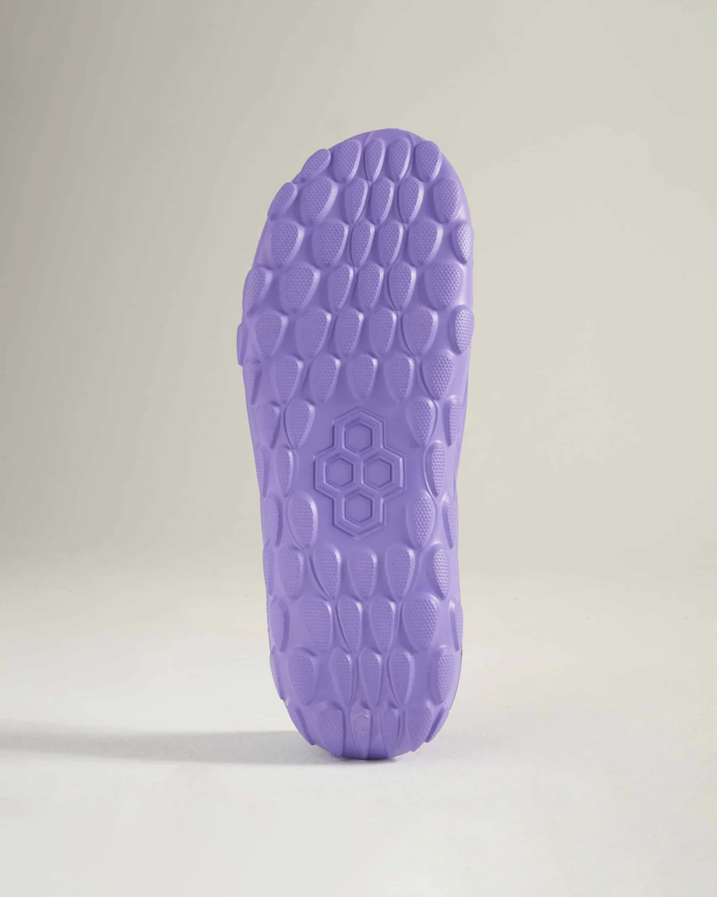 The image features a close-up view of a textured purple shoe sole highlighting its hexagonal pattern and unique design elements