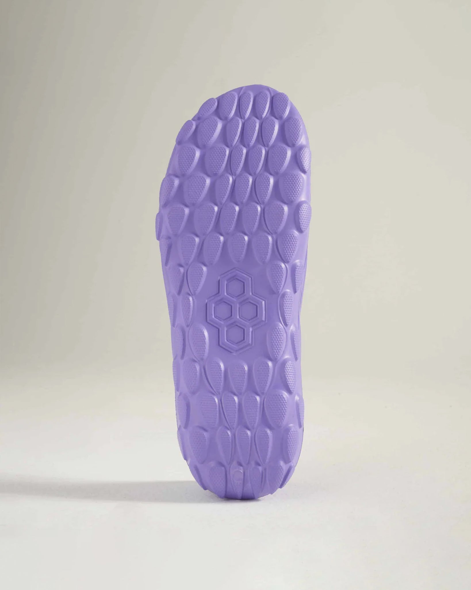 The image features a close-up view of a textured purple shoe sole highlighting its hexagonal pattern and unique design elements