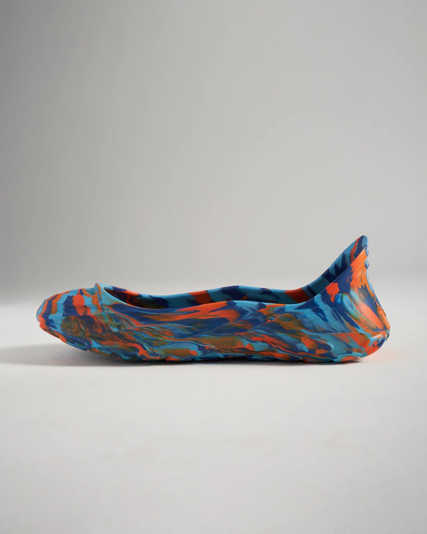 A stylized side view of a colorful shoe featuring a swirling pattern in blue orange and patches of other colors showcasing a unique design