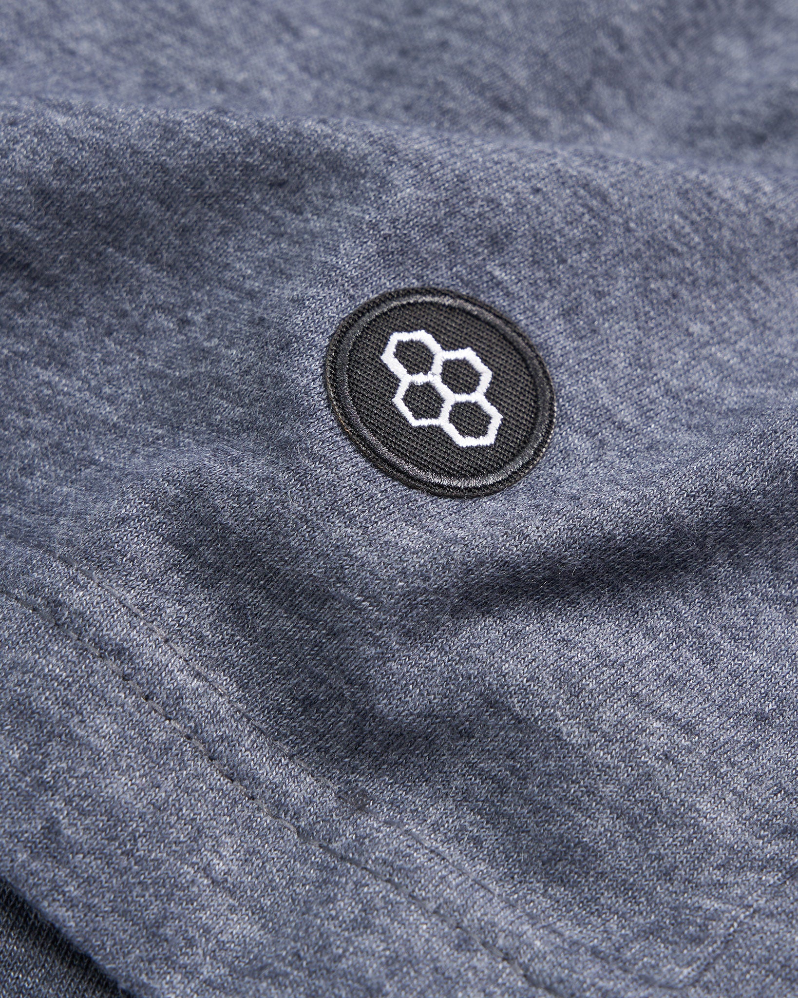 Close-up of a dark gray fabric featuring a round black patch with a geometric honeycomb design in white