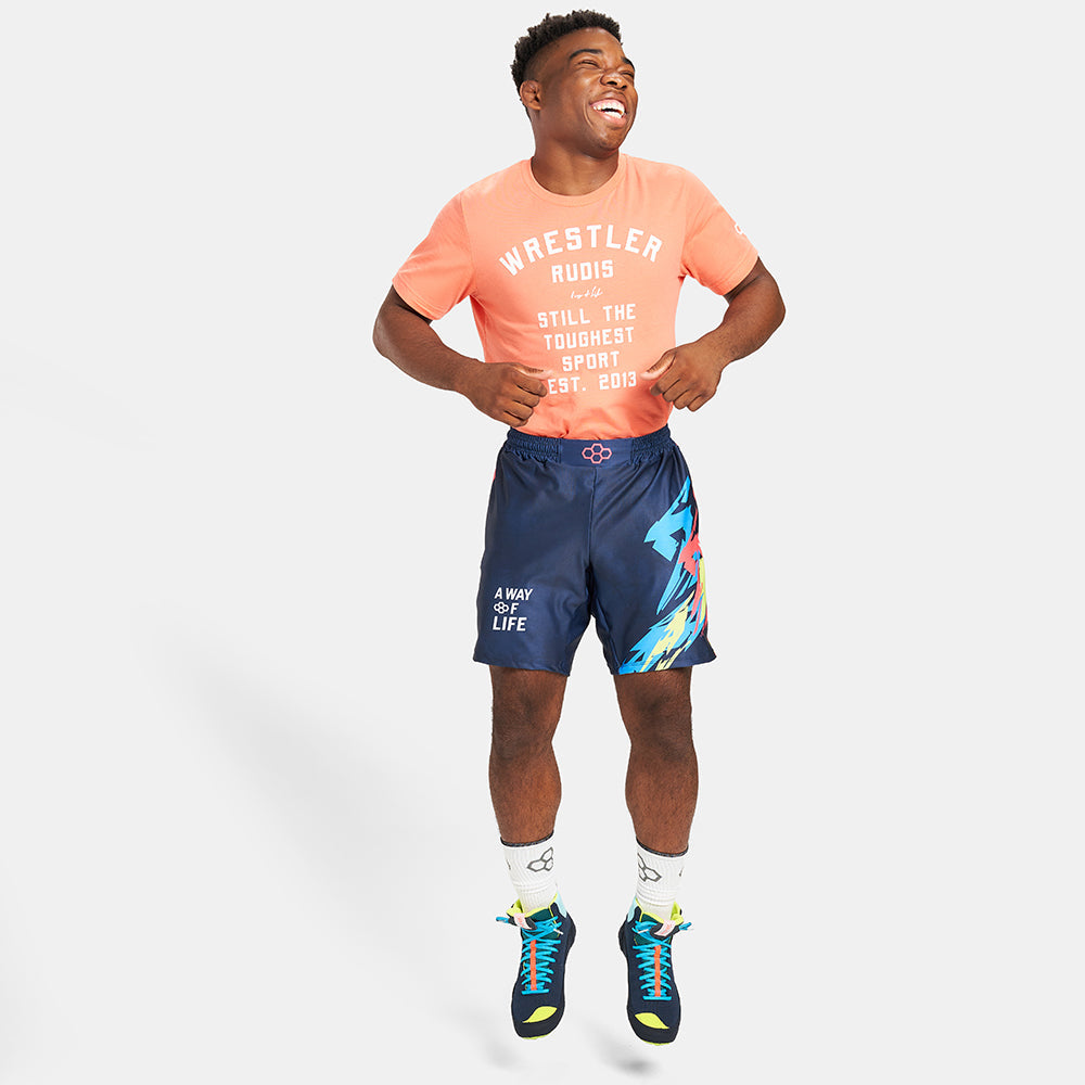 A cheerful young athlete wearing a vibrant orange t-shirt and navy blue shorts showcasing dynamic graphics and athletic shoes exuding energy and enthusiasm