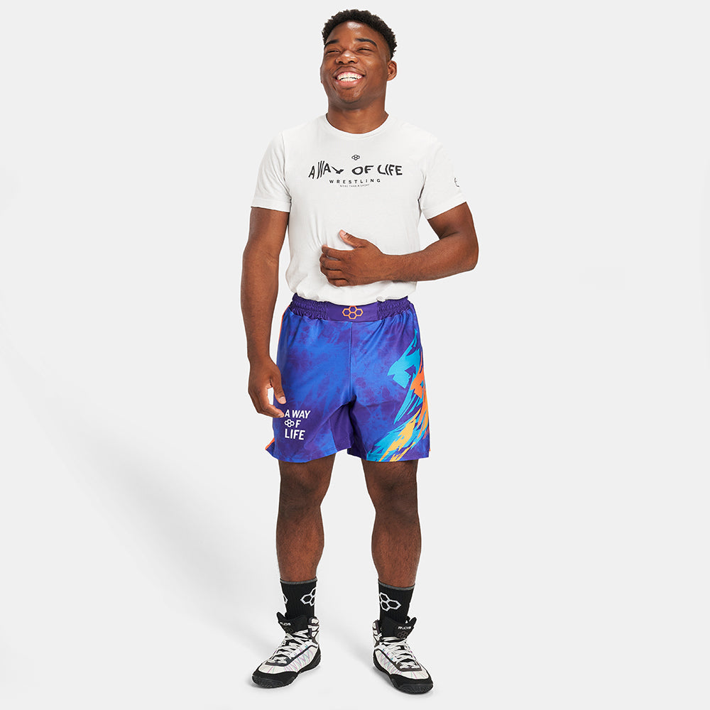 A joyful young man wearing a white T-shirt and colorful purple shorts standing casually with a smile showcasing a fun and sporty style