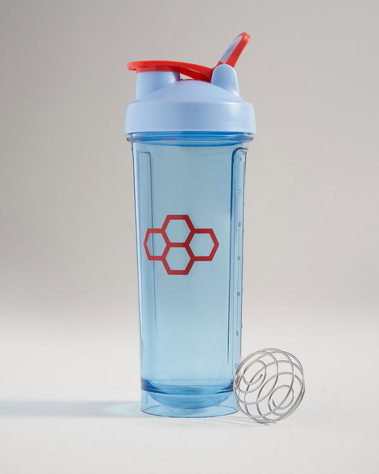 A blue shaker bottle with a red lid and a honeycomb logo accompanied by a stainless steel whisk ball for mixing ingredients