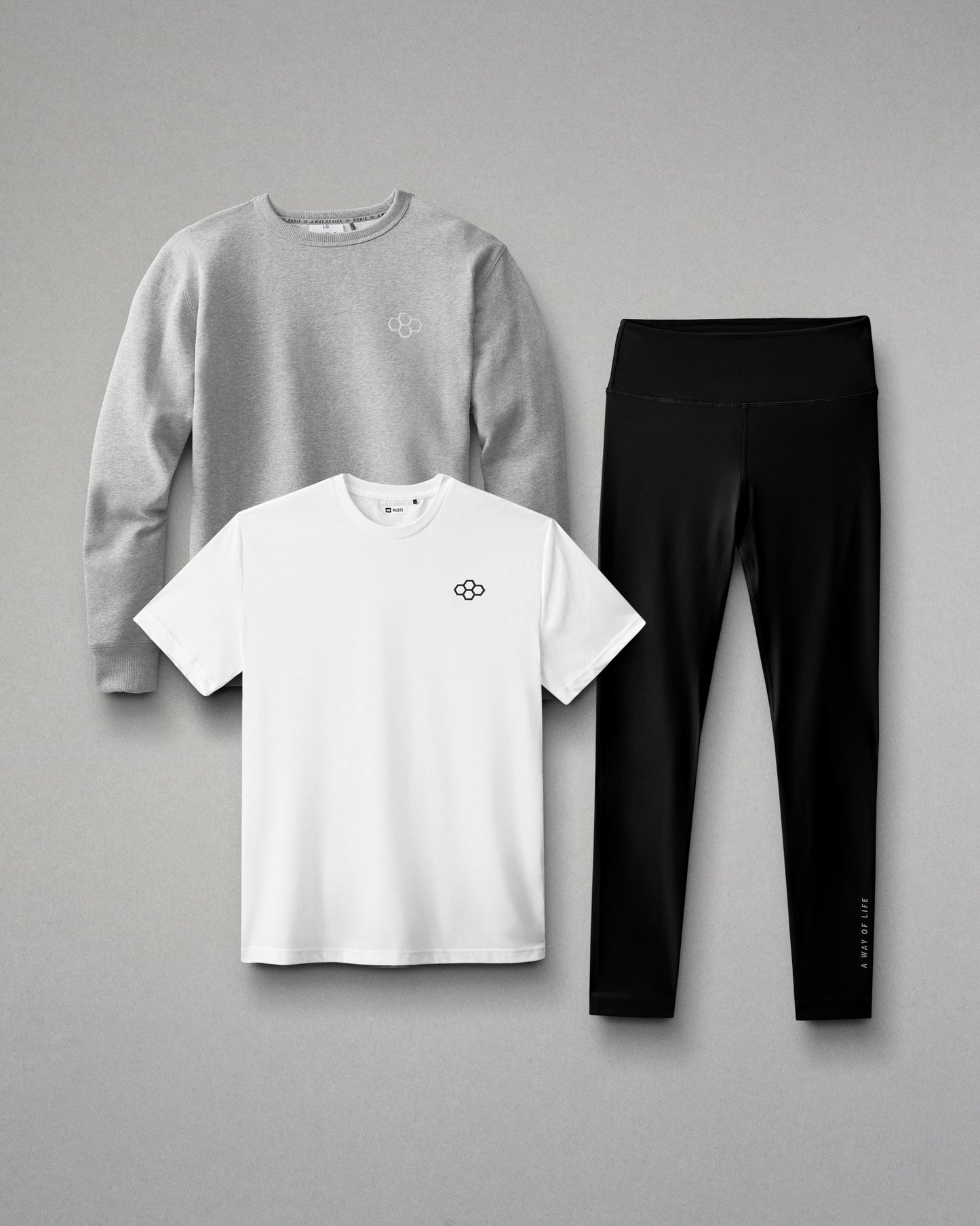 Gray sweatshirt, white t-shirt, and black leggings arranged on a gray background