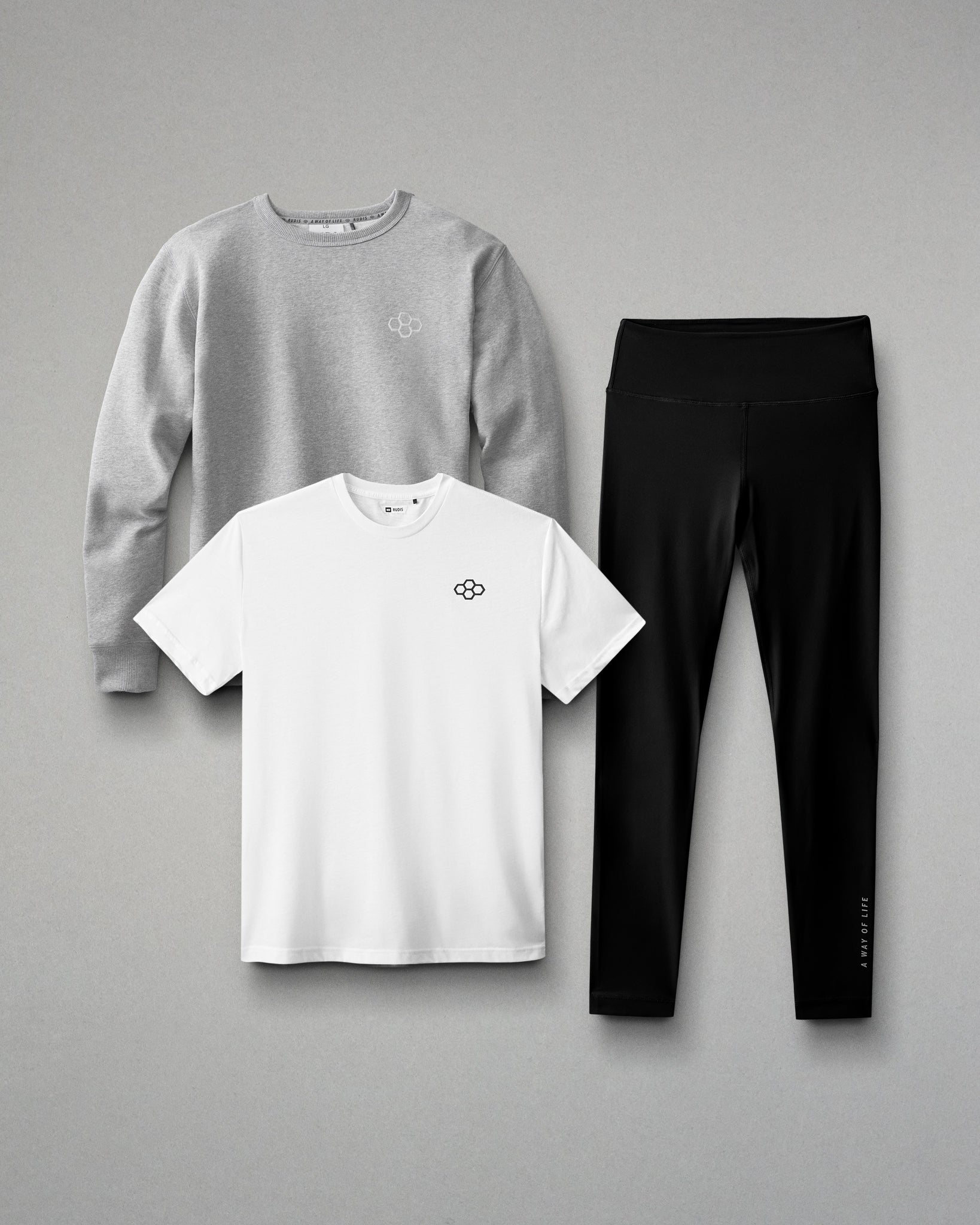 Gray sweatshirt, white t-shirt, and black leggings arranged on a gray background
