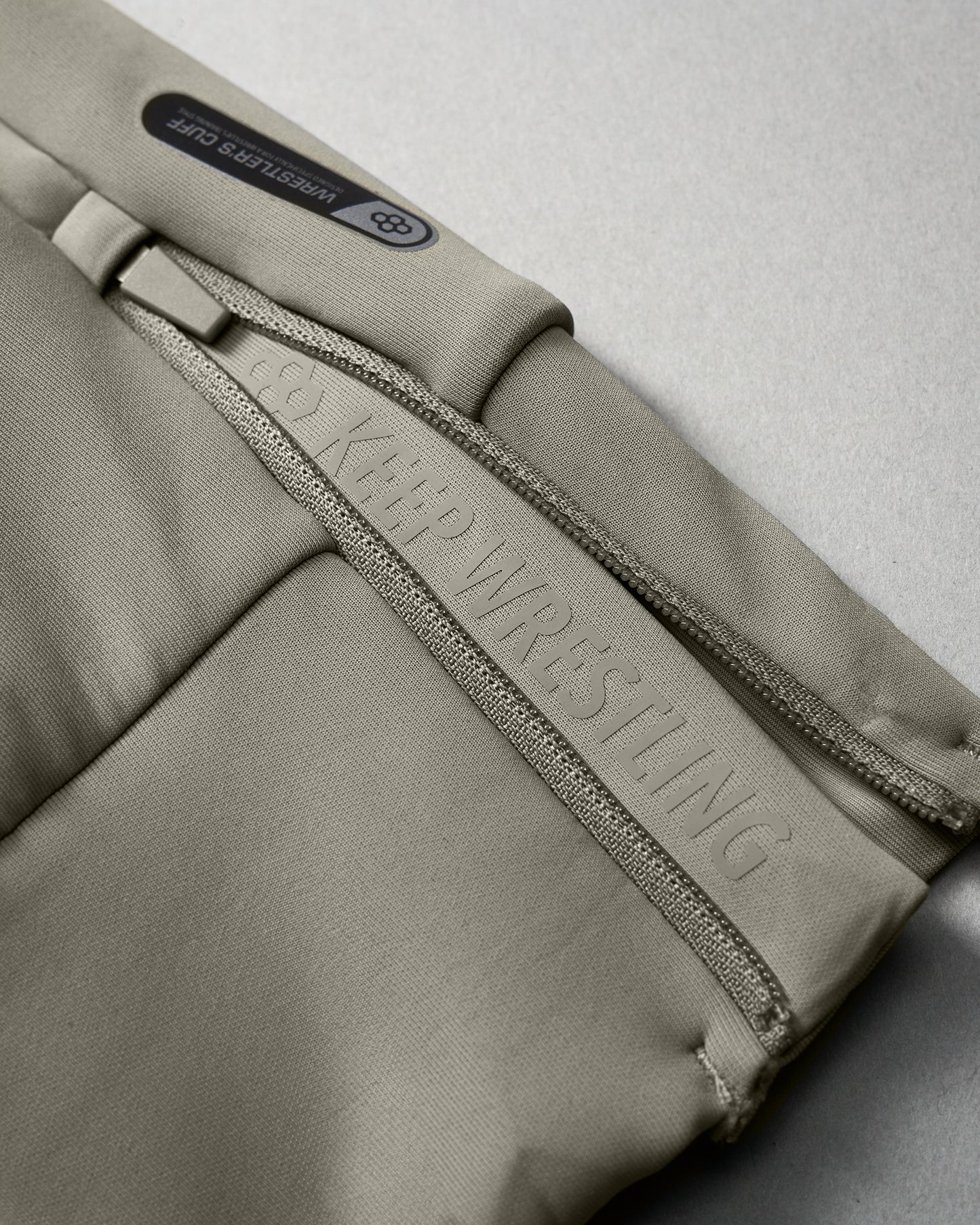 Close-up of a green wrestling uniform with 'Keep Wrestling' branding on a gray background