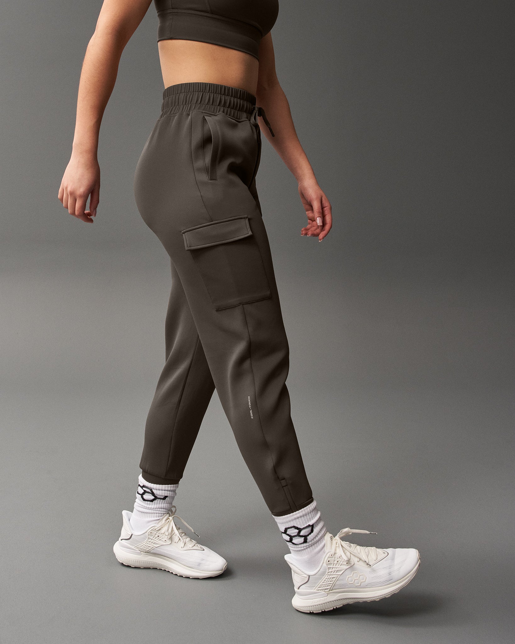 Person wearing dark cargo jogger pants on a gray background