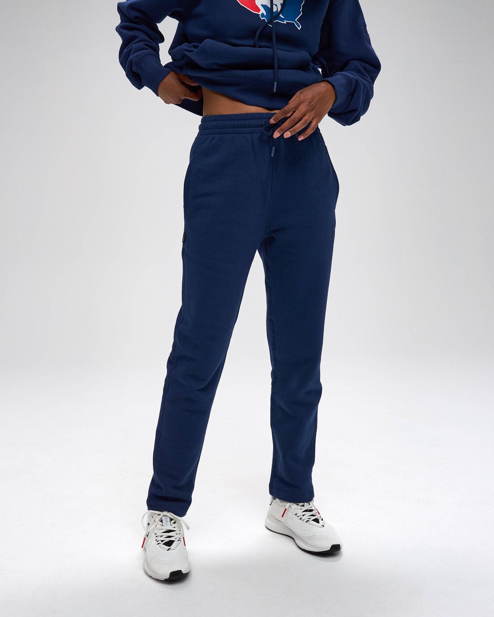 Person wearing a navy tracksuit with a logo on a white background