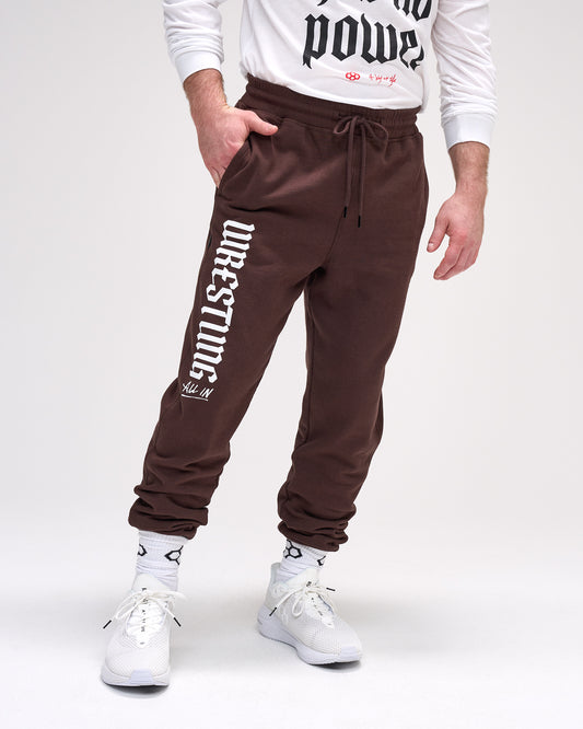 Person wearing brown 'Wrestling' sweatpants on a white background