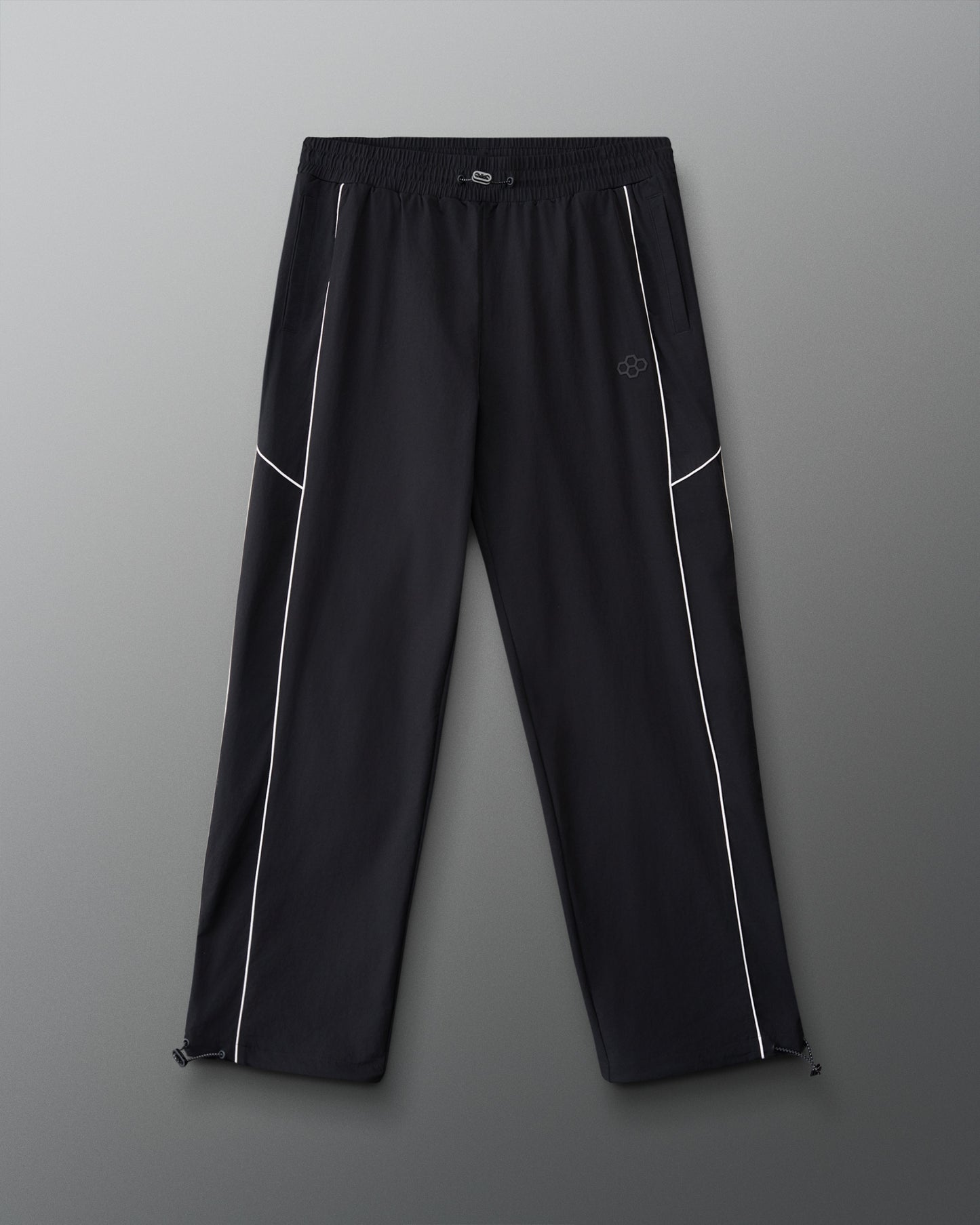 Front view of RUDIS Movement Podium Pants in black with white piping, elastic waistband, side pockets, and subtle RUDIS logo.