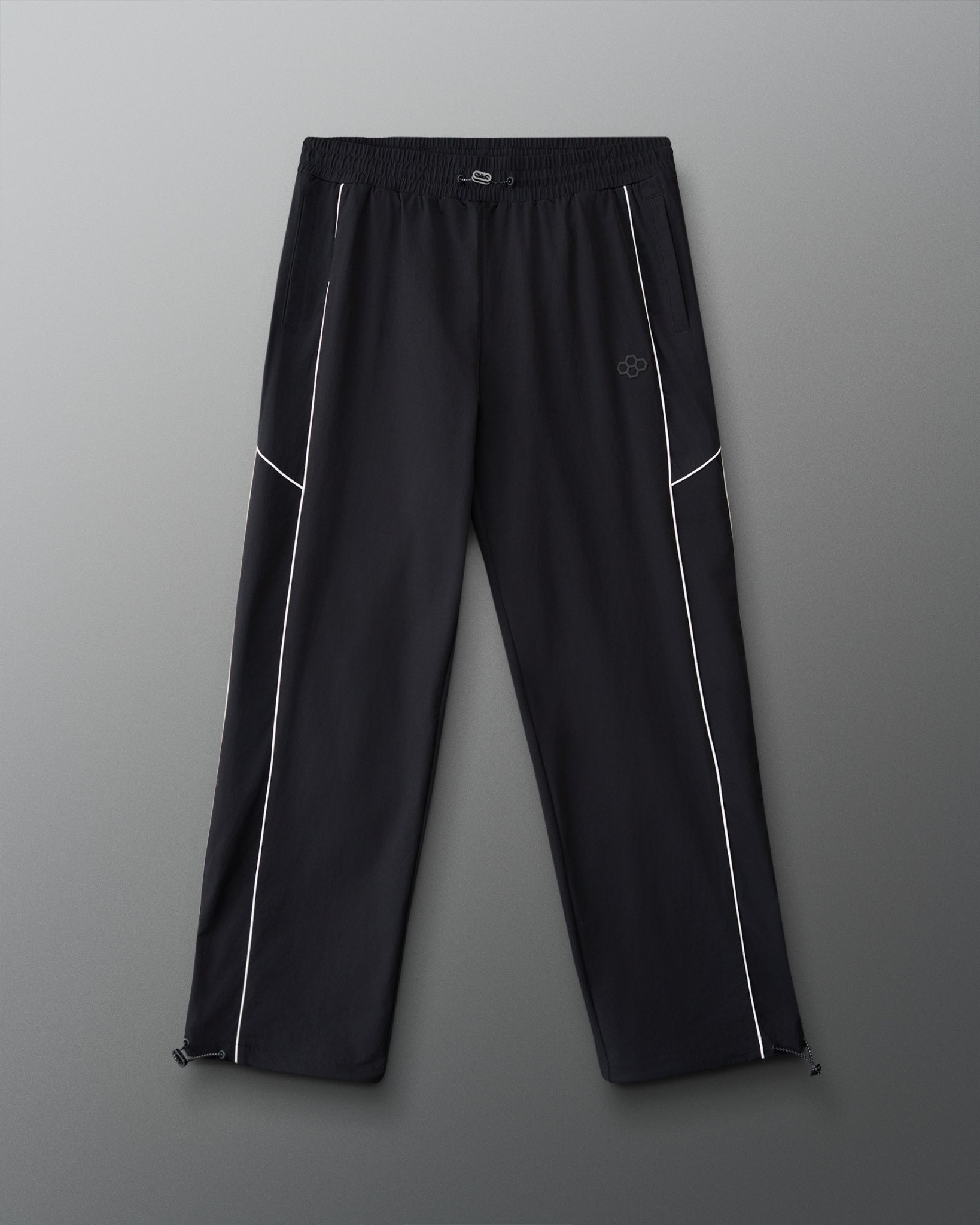Front view of RUDIS Movement Podium Pants in black with white piping, elastic waistband, side pockets, and subtle RUDIS logo.