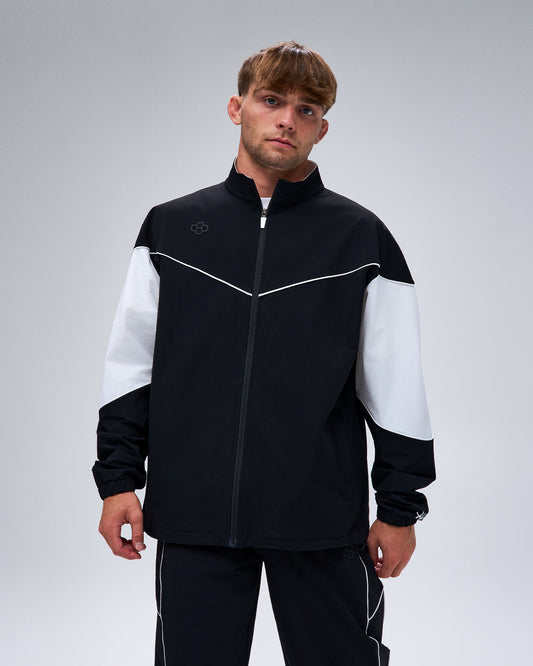 Model wearing the black RUDIS Full-Zip Movement Podium Jacket with white color-block sleeves and contrast piping.