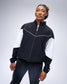 Model wearing the black RUDIS Full-Zip Movement Podium Jacket, featuring white sleeve panels, contrast piping, and RUDIS logo.