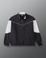 Front view of the RUDIS Full Zip Movement Podium Jacket in black with white sleeve panels, full-zip closure, and RUDIS logo.
