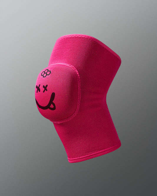 Pink knee pad with a smiley face design on a gray background