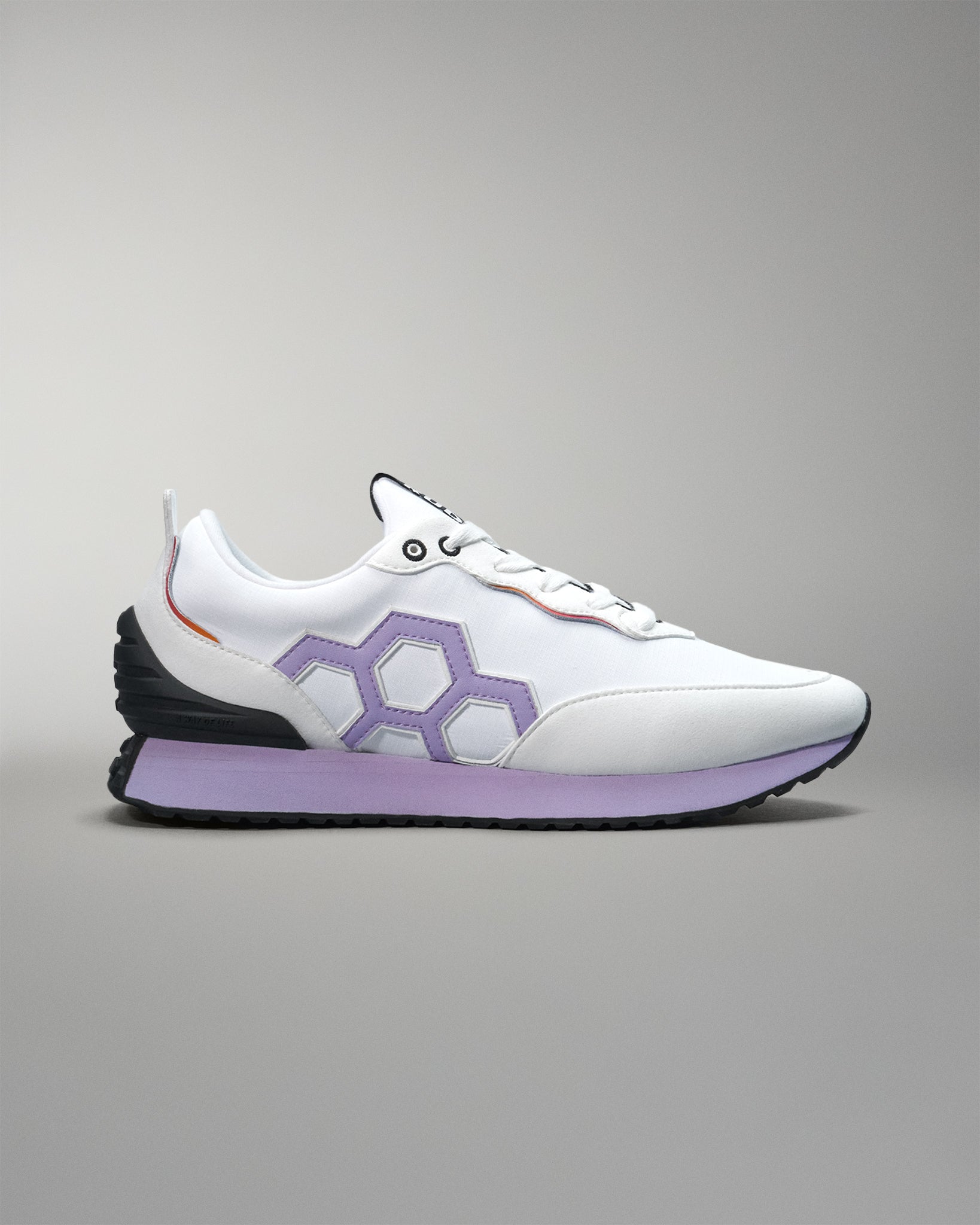 White sneaker with purple sole on a gray background