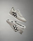 A pair of white RUDIS Street Adult Lifestyle Shoes with a large black hex logo on the side, displayed against a grey background.