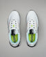 White sneakers with black and green accents on a gray background