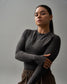 Woman wearing a dark gray long-sleeve top against a plain background