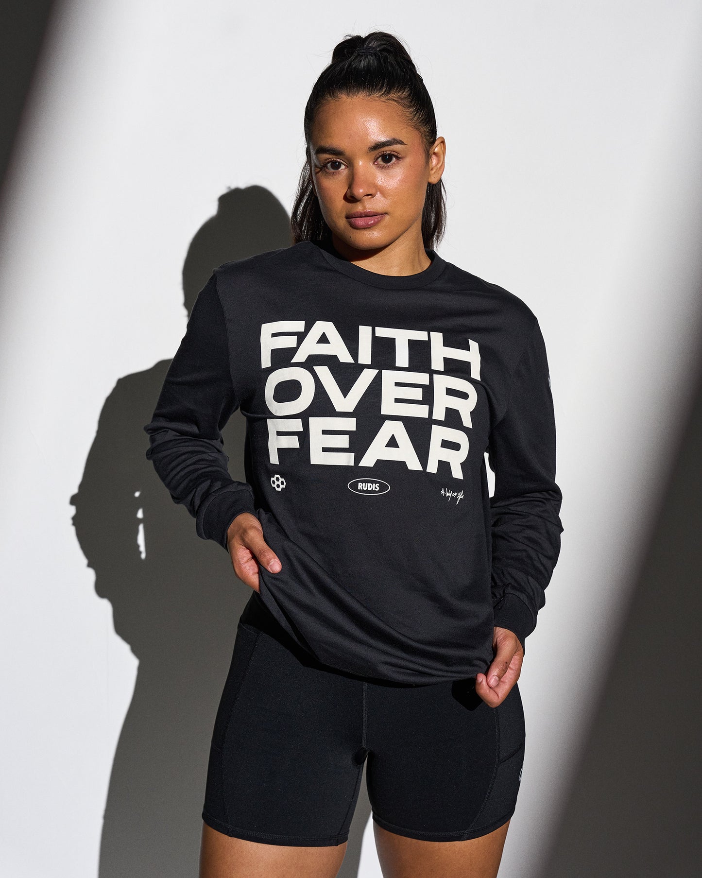 Person wearing a black sweatshirt with 'Faith Over Fear' text on a white background