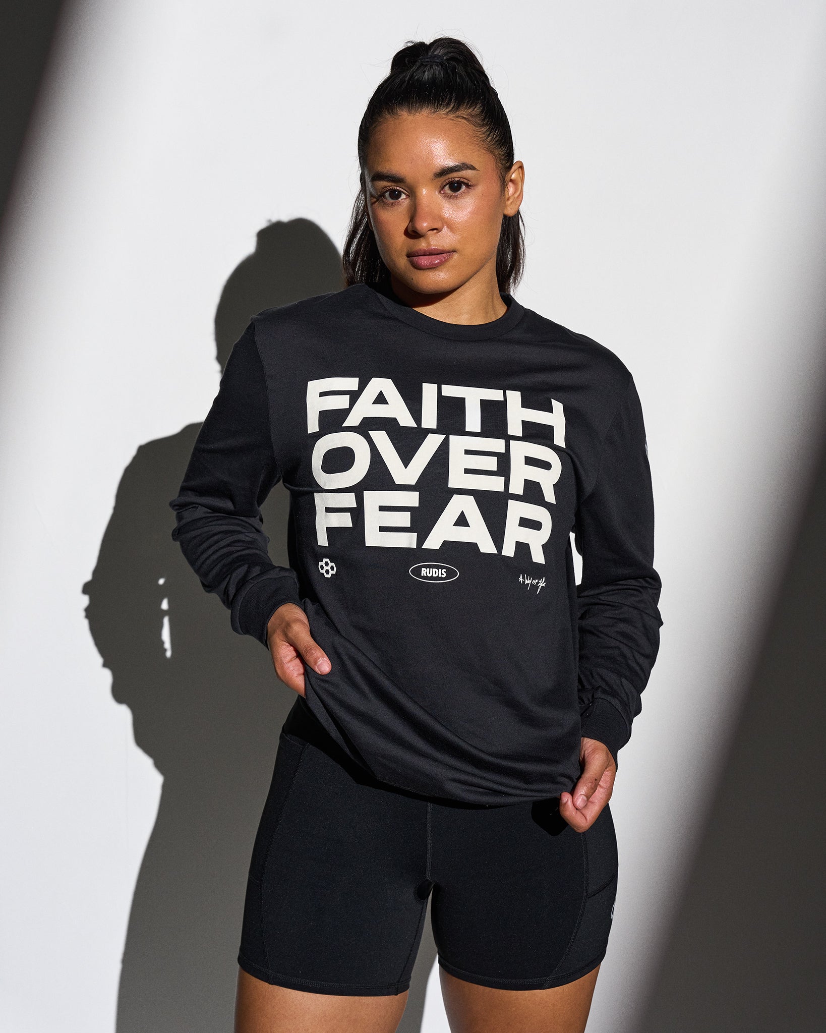Person wearing a black sweatshirt with 'Faith Over Fear' text on a white background