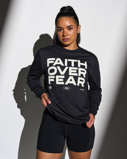 Person wearing a black sweatshirt with 'Faith Over Fear' text on a white background