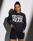 Person wearing a black sweatshirt with 'Faith Over Fear' text on a white background
