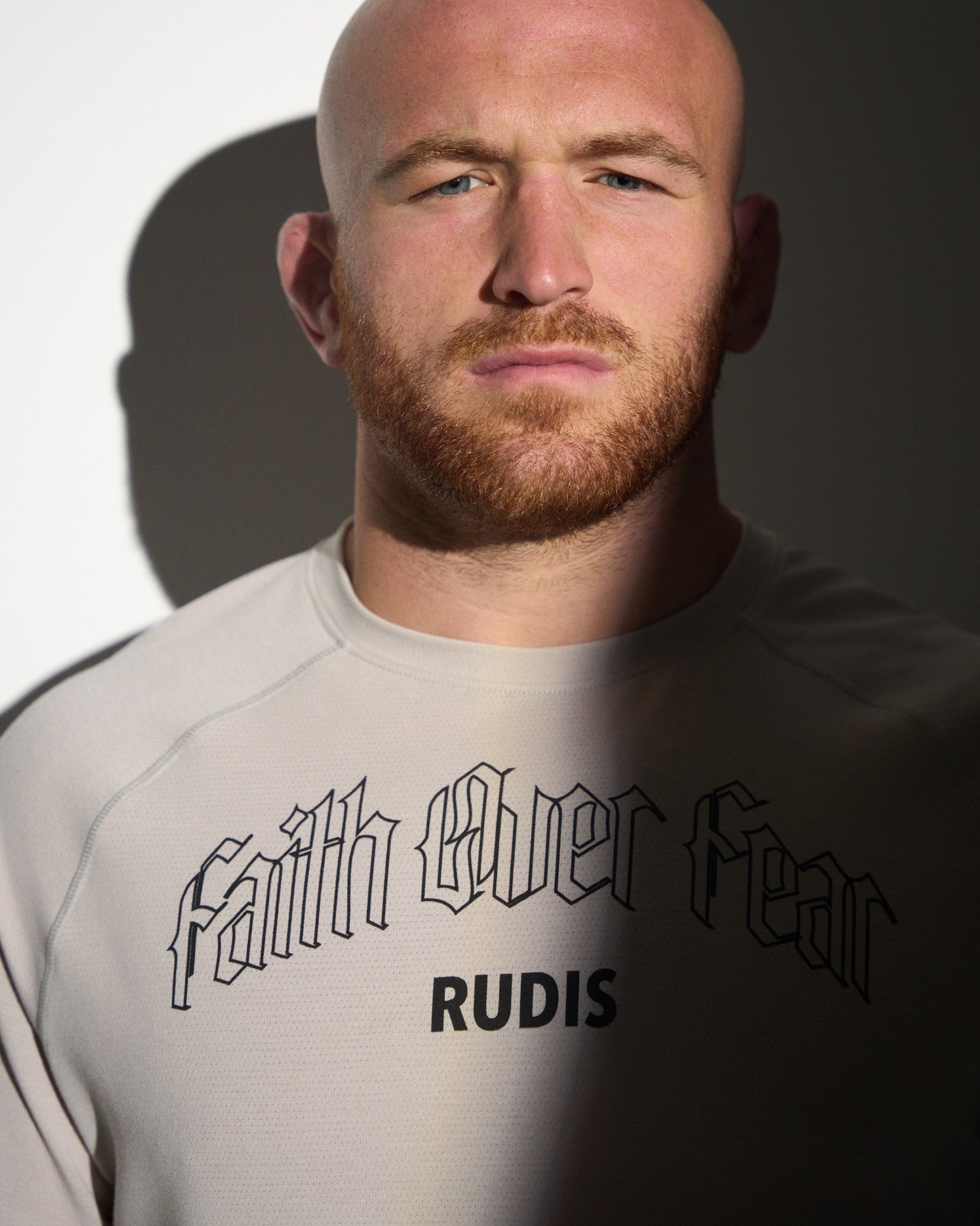 Athlete wearing the RUDIS Faith Over Fear Tech Thermal in Bone, showcasing gothic-inspired "Faith Over Fear" graphics, moisture-wicking performance fabric, and a lightweight athletic fit for training and the wrestling lifestyle.