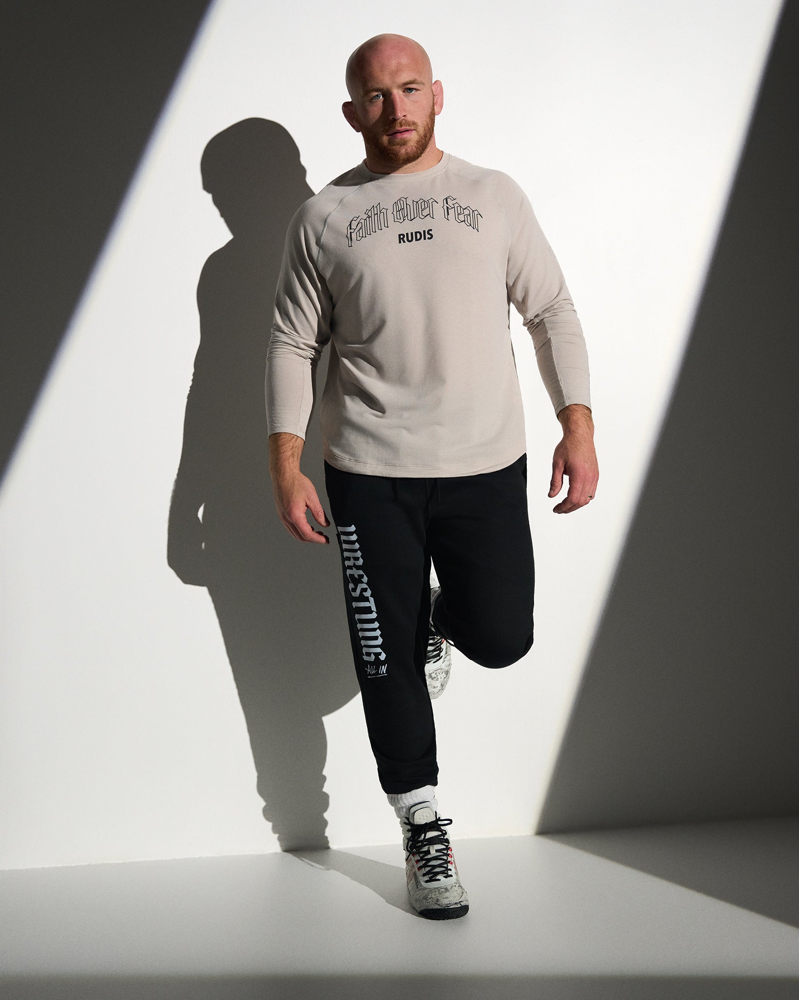 RUDIS Faith Over Fear Tech Thermal in Bone styled with black Gothic Wrestling Titan Heavyweight Joggers, featuring breathable performance fabric, gothic-inspired graphics, and a versatile athletic fit.