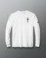 A white long-sleeve crewneck t-shirt with a black cross printed on the left chest and a small black logo on the right sleeve, displayed against a dark gray gradient background.
