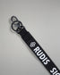Close-up of the black RUDIS Wordmark lanyard featuring a durable metal key clip, key ring, woven polyester strap, and bold white RUDIS logo with honeycomb icon.