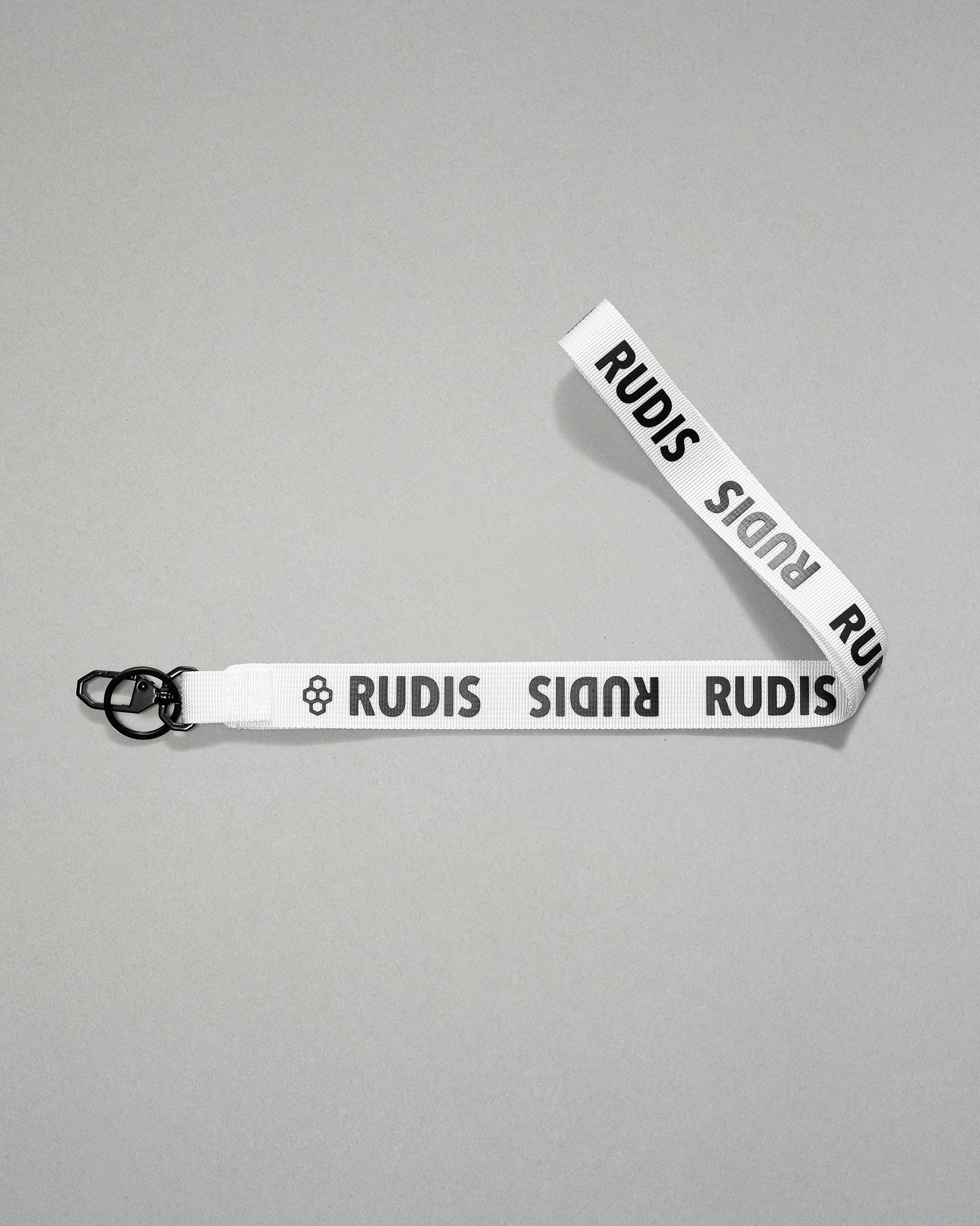 white RUDIS Wordmark lanyard with repeating white RUDIS logos, woven polyester strap, metal key clip, and key ring for carrying keys, badges, or accessories.