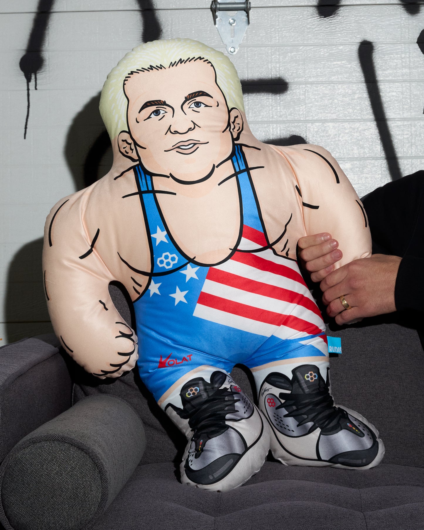 Pillow figure of a muscular man in an American flag singlet on a chair.