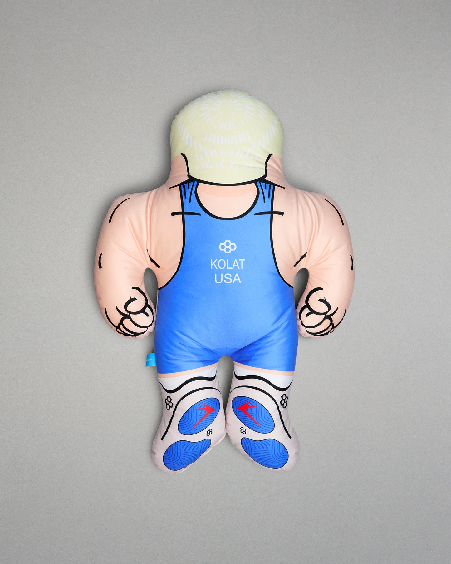 Pillow figure of a muscular character wearing a blue wrestling singlet with 'Kolat USA' branding on a gray background.