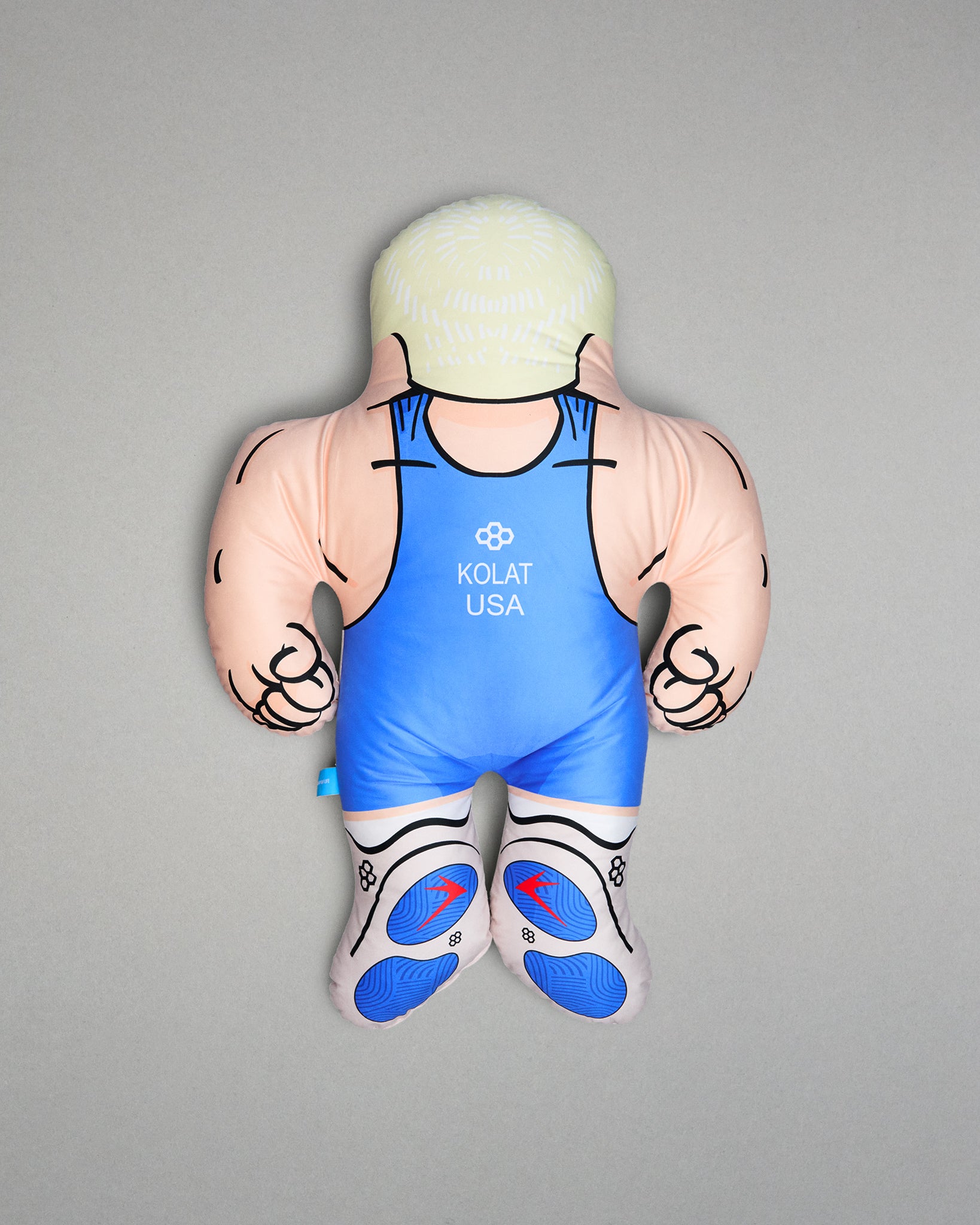 Pillow figure of a muscular character wearing a blue wrestling singlet with 'Kolat USA' branding on a gray background.