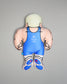 Pillow figure of a muscular character wearing a blue wrestling singlet with 'Kolat USA' branding on a gray background.