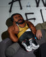 Pillow figure of a person wearing a wrestling singlet with wrestling shoes on a couch.