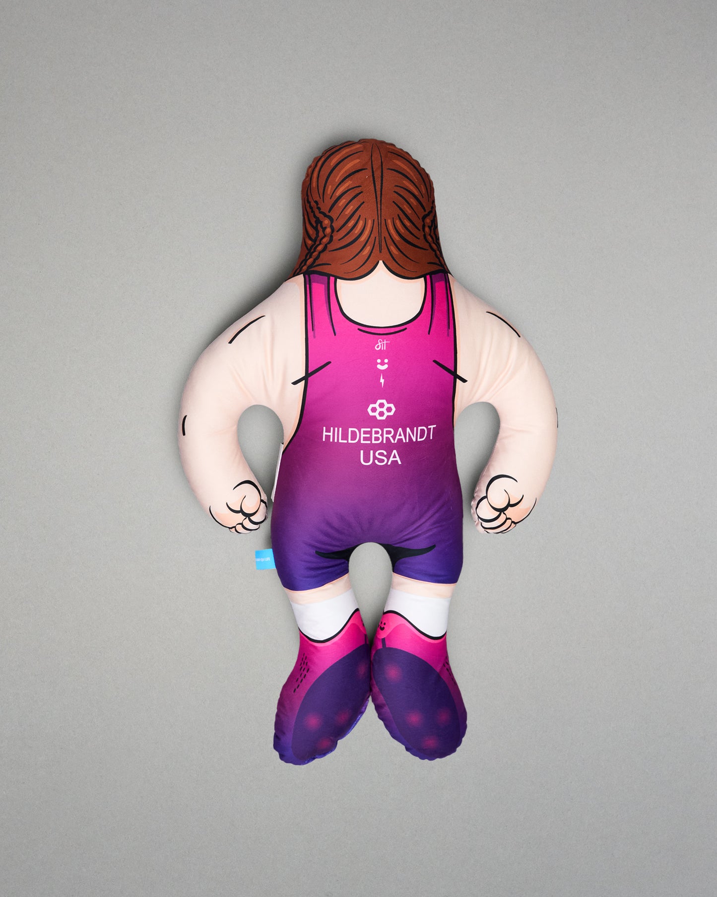 Pillow figure of a wrestler in a pink and purple singlet on a gray background