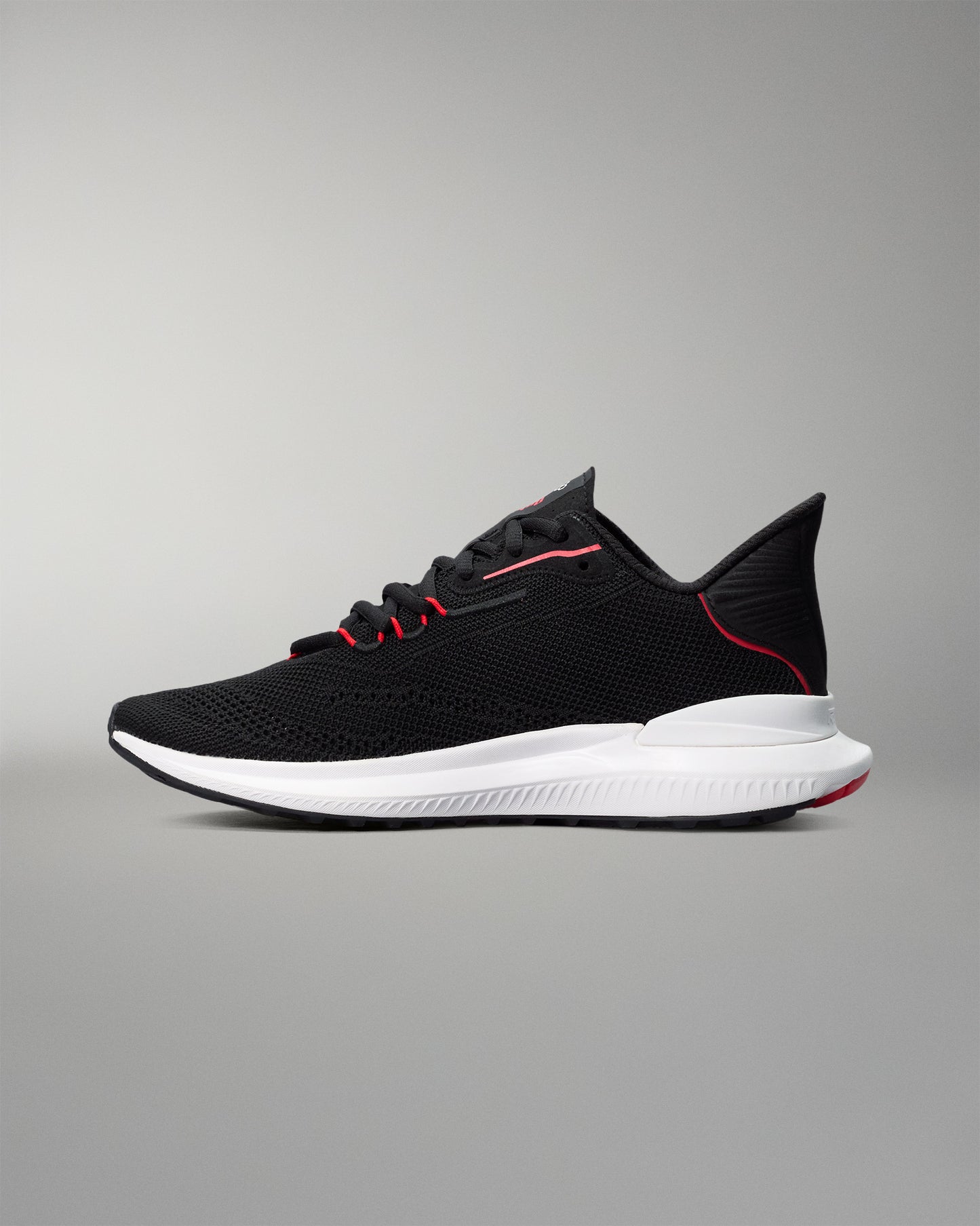 Black running shoe with white sole on a gray background