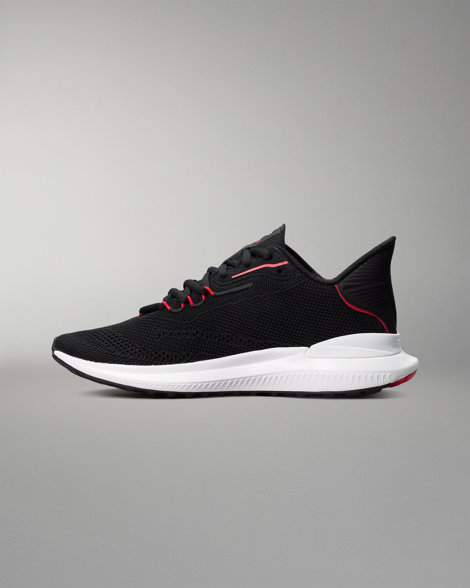 Black running shoe with white sole on a gray background